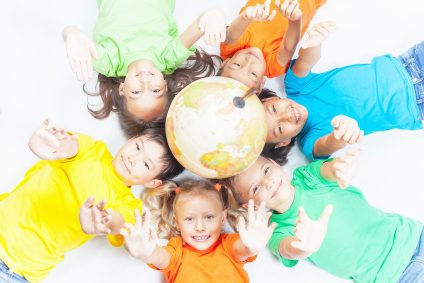 Group of international funny kids. Lying with globe earth, looking up at camera. Smiling. School children learn geography. Multi Ethnic people. World. Ecology. Pure earth. International Children's Day