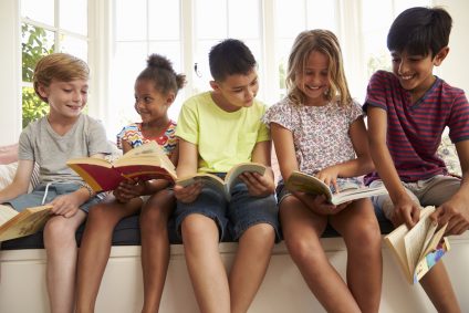 Group Of Multi-Cultural Children Reading On Window Seat