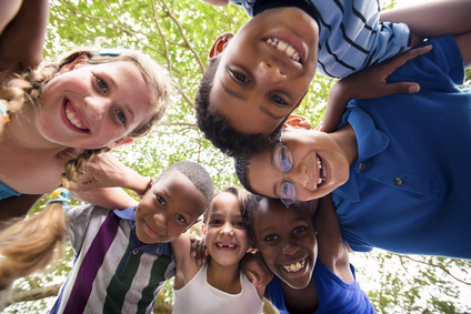 Group of happy female and male kids having fun and hugging around the camera. Low angle view